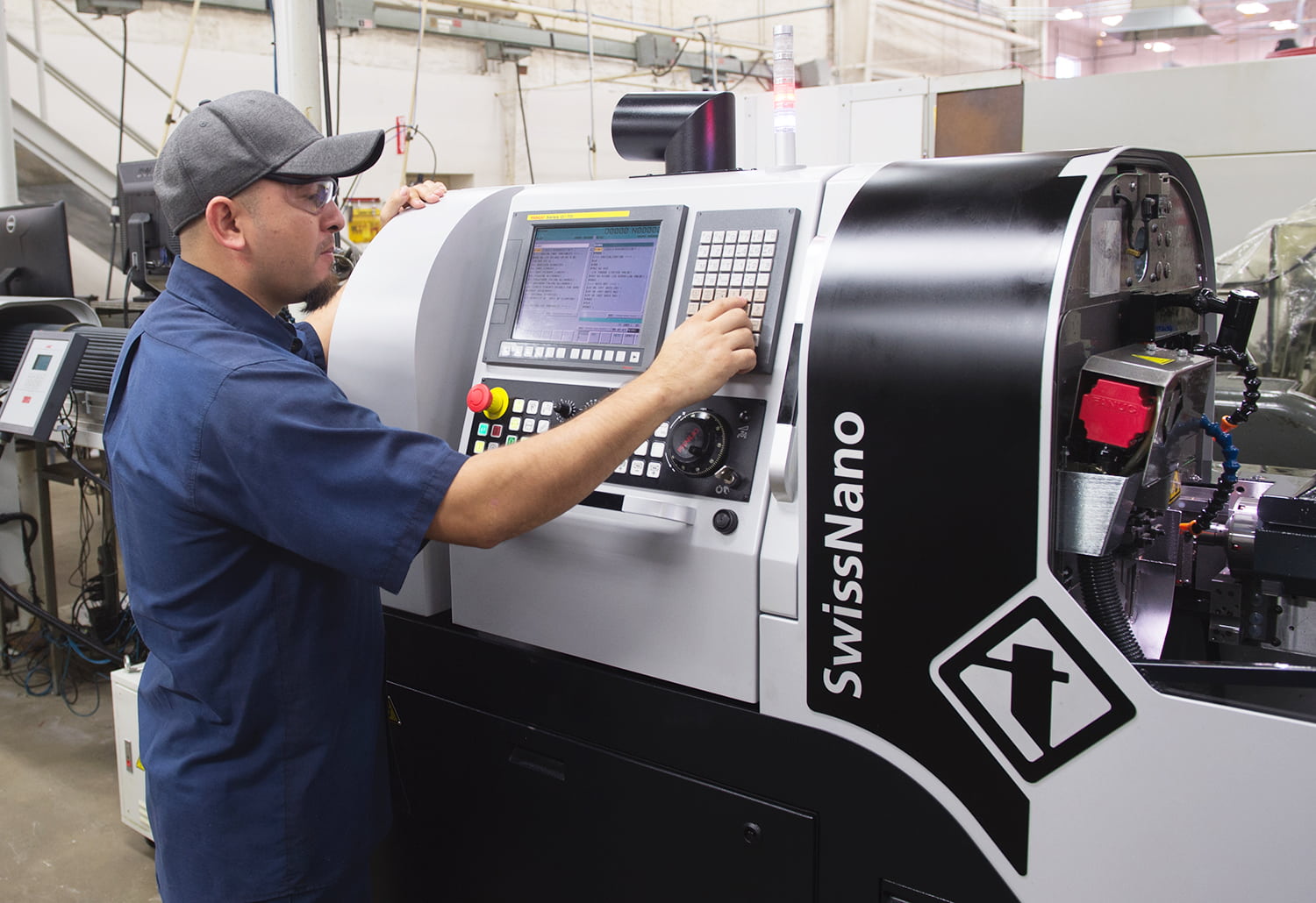 Isreal, a year 3 machinist apprentice, operates a Tornos SwissNano machine with FANUC Series 0i-TD controls.